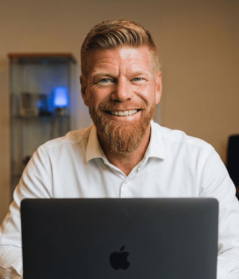 Trond Magnus Gulbrandsen. Han sidder på et kontor med en macbook foran sig.
